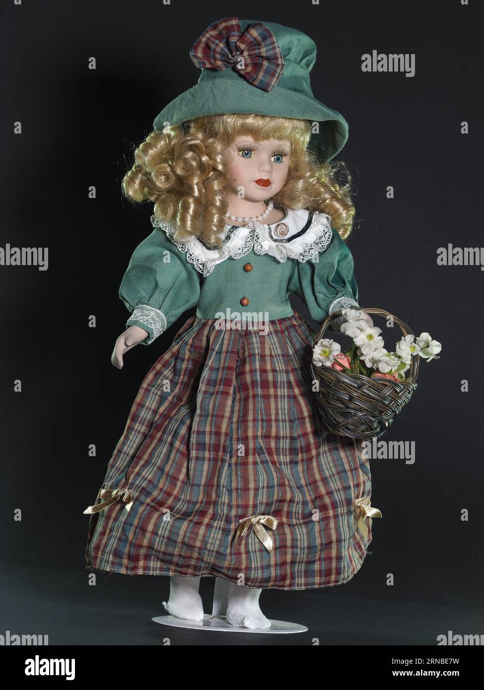 Vintage fille de poupée allemande en porcelaine, yeux bleus, blonde avec des cheveux bouclés fluides dans un chapeau vert et un costume allemand traditionnel d'une veste verte et un Banque D'Images