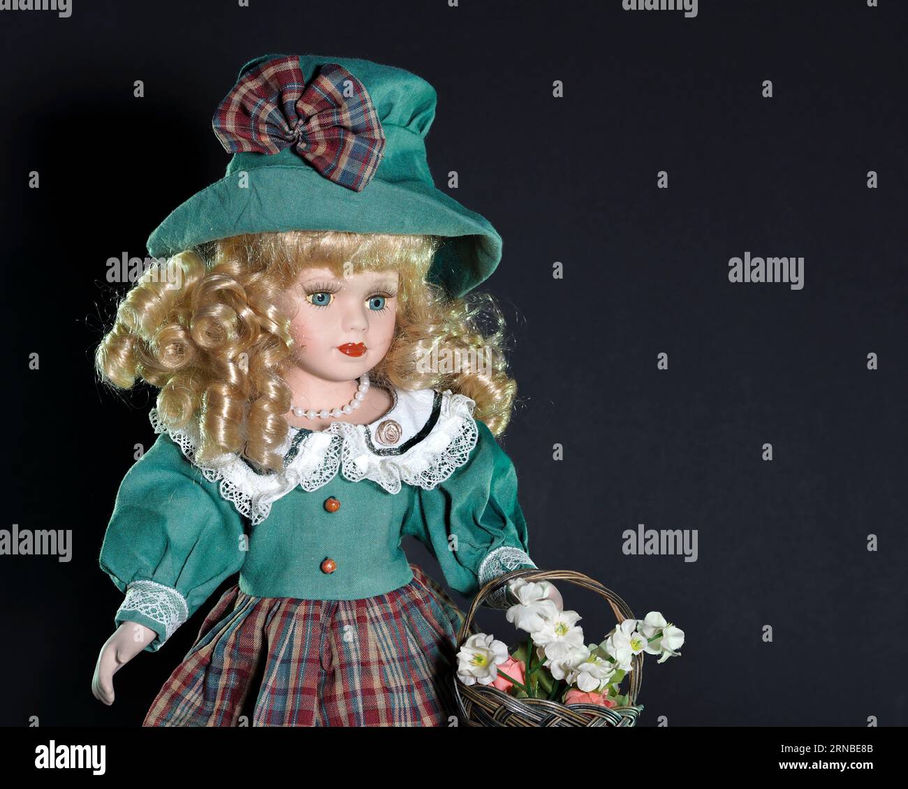 Vintage fille de poupée allemande en porcelaine, yeux bleus, blonde avec des cheveux bouclés fluides dans un chapeau vert et un costume allemand traditionnel d'une veste verte et un Banque D'Images