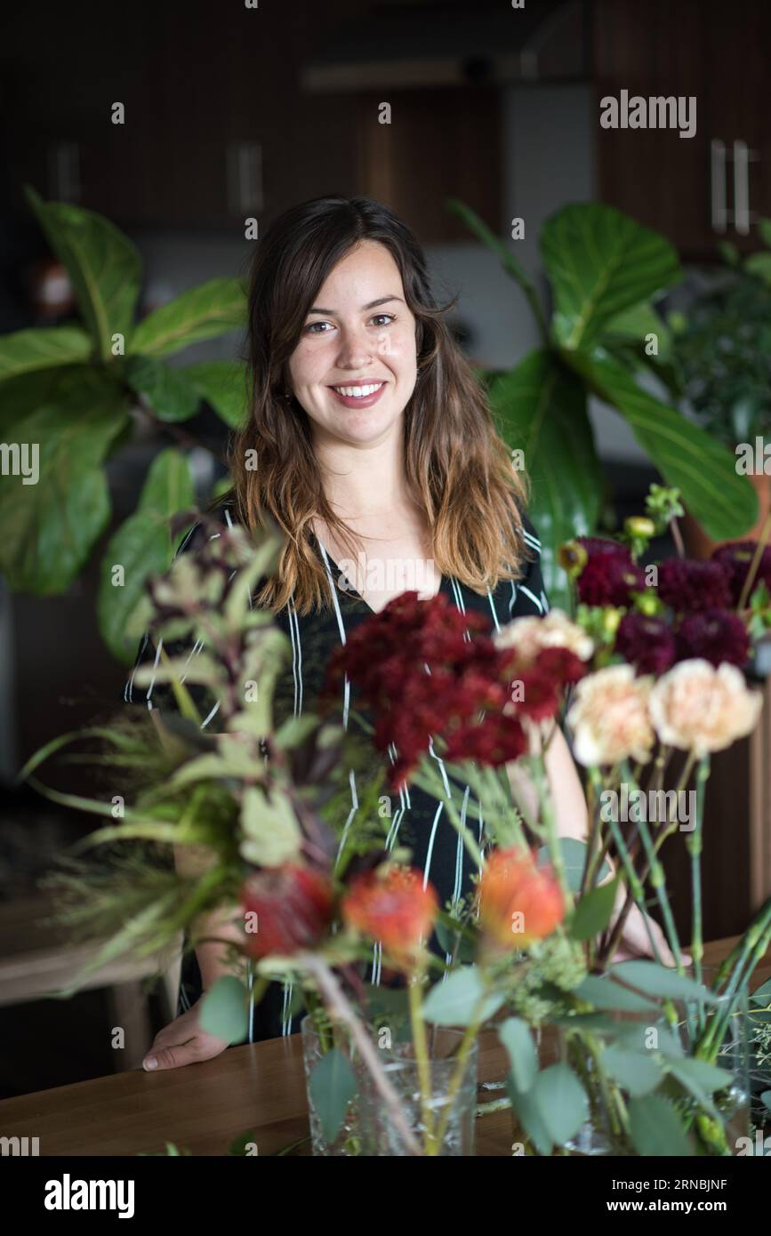 Femme souriante entourée de plantes d'intérieur dans l'appartement Banque D'Images