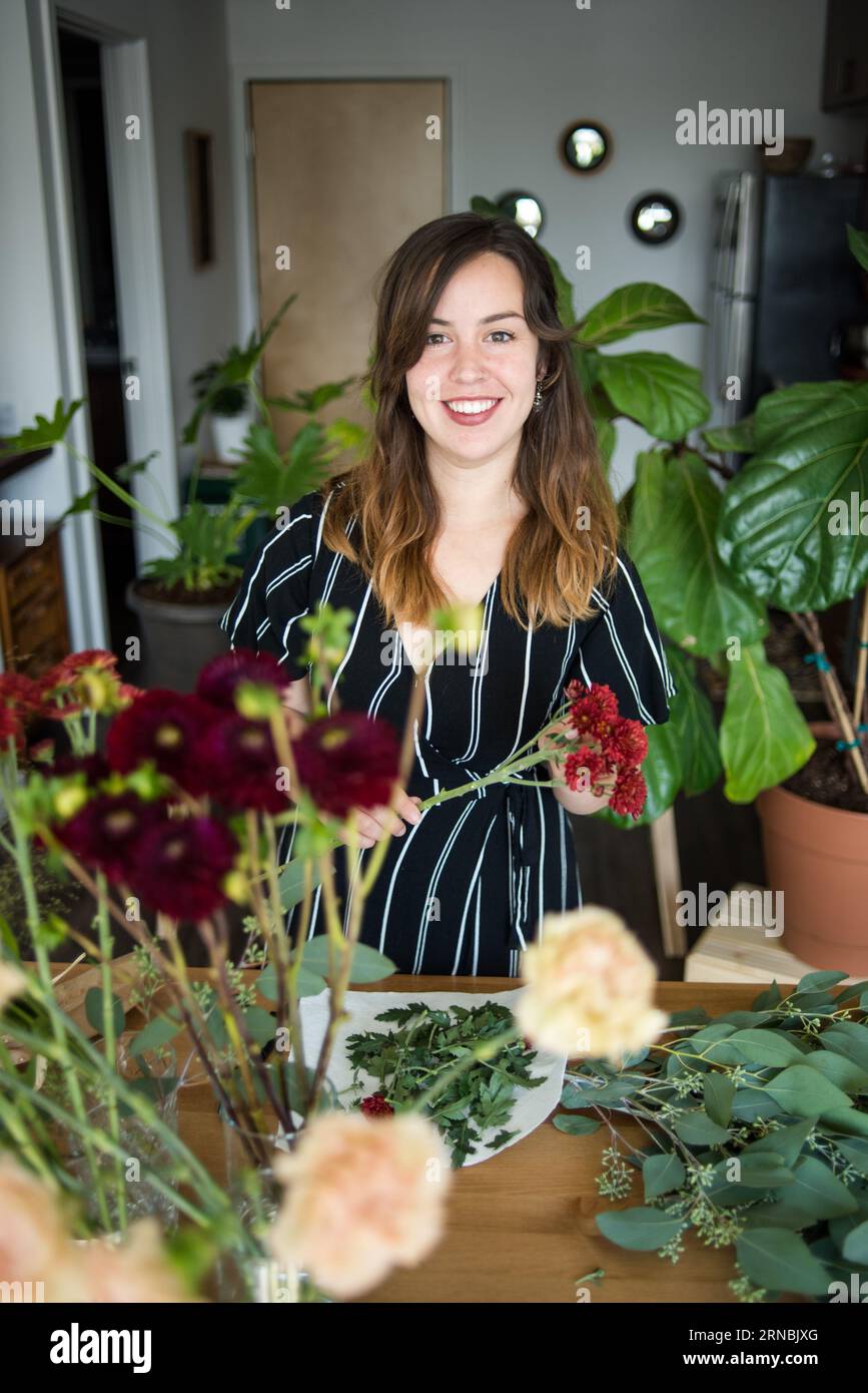 Portrait souriant de femme tenant des tiges de fleurs Banque D'Images