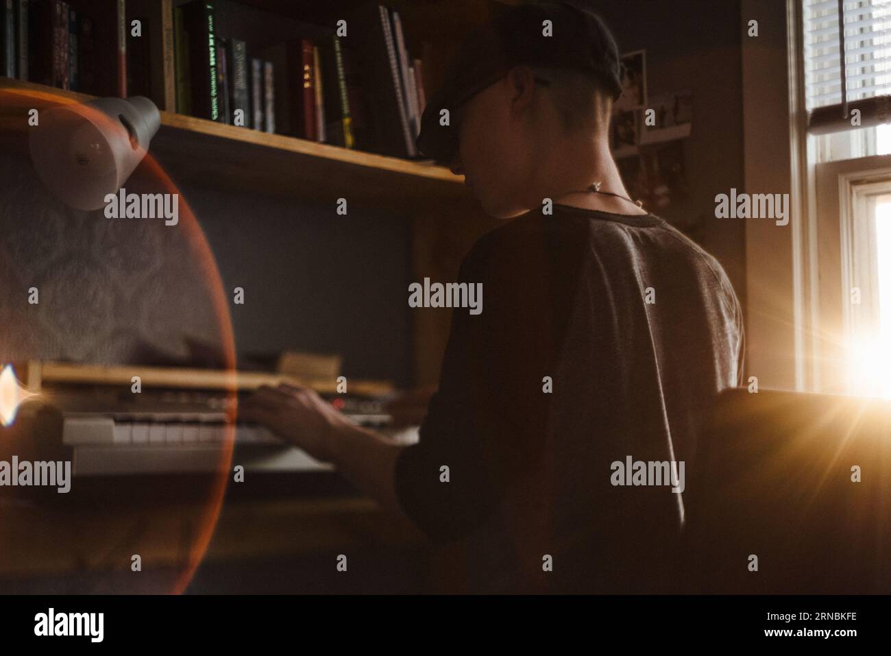 Adolescent garçon joue le clavier dans la chambre au coucher du soleil Banque D'Images