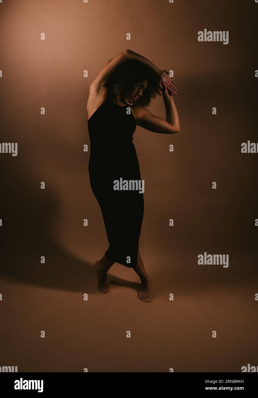 La danseuse noire fait de la danse contemporaine pose dans la lumière du studio Banque D'Images