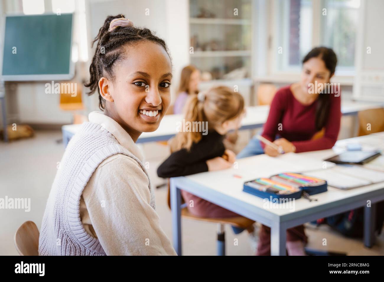 Portrait vue de côté d'une étudiante souriante assise dans la salle de classe Banque D'Images