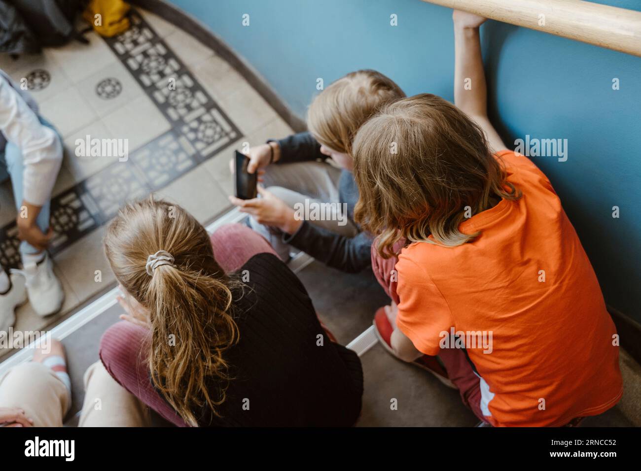 Vue à angle élevé des amis masculins et féminins assis sur l'escalier du bâtiment de l'école Banque D'Images
