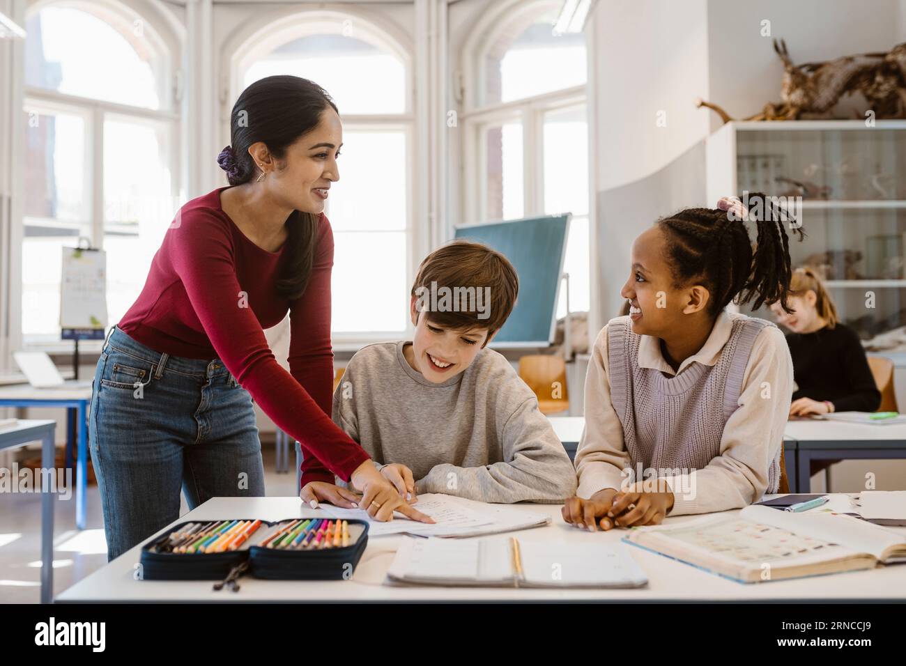 Professeur heureux regardant l'étudiante tout en aidant dans la salle de classe Banque D'Images