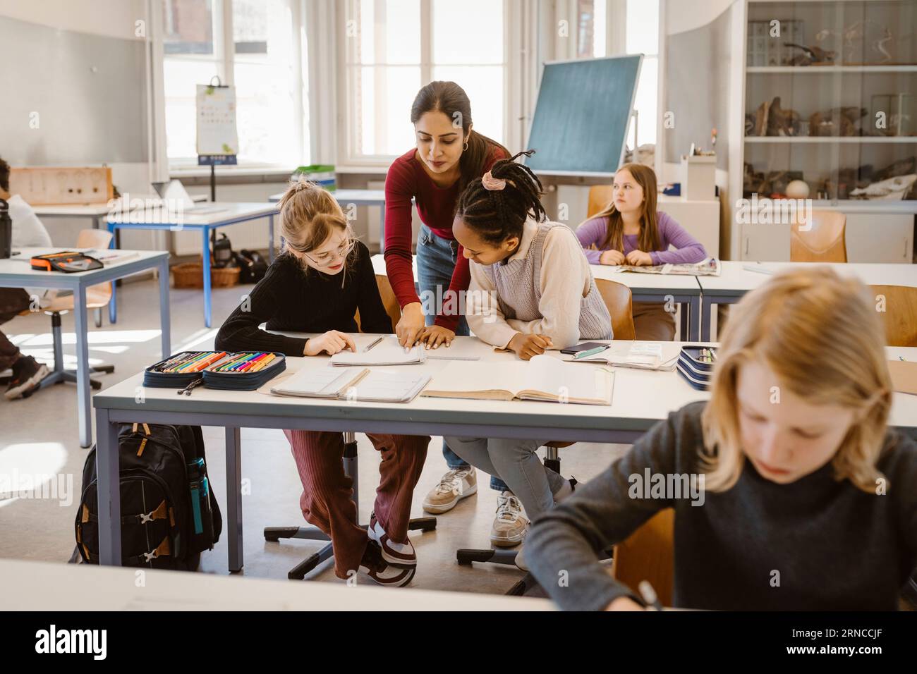 Enseignant expliquant les élèves des écoles masculins et féminins assis au bureau dans la salle de classe Banque D'Images