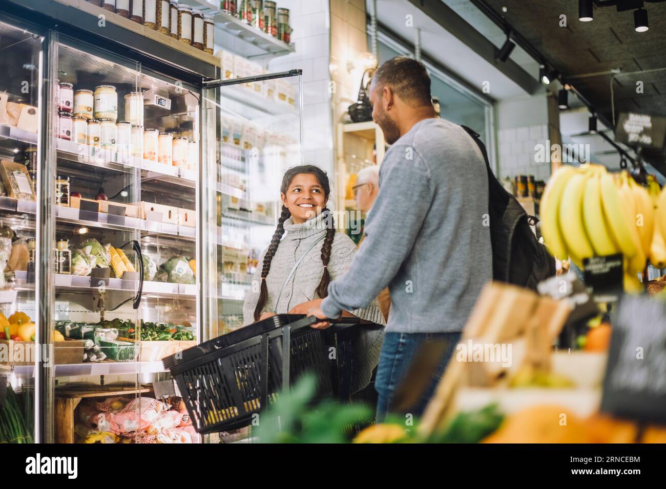 Fille souriante magasinant pour l'épicerie avec le père à Delicatessen Banque D'Images