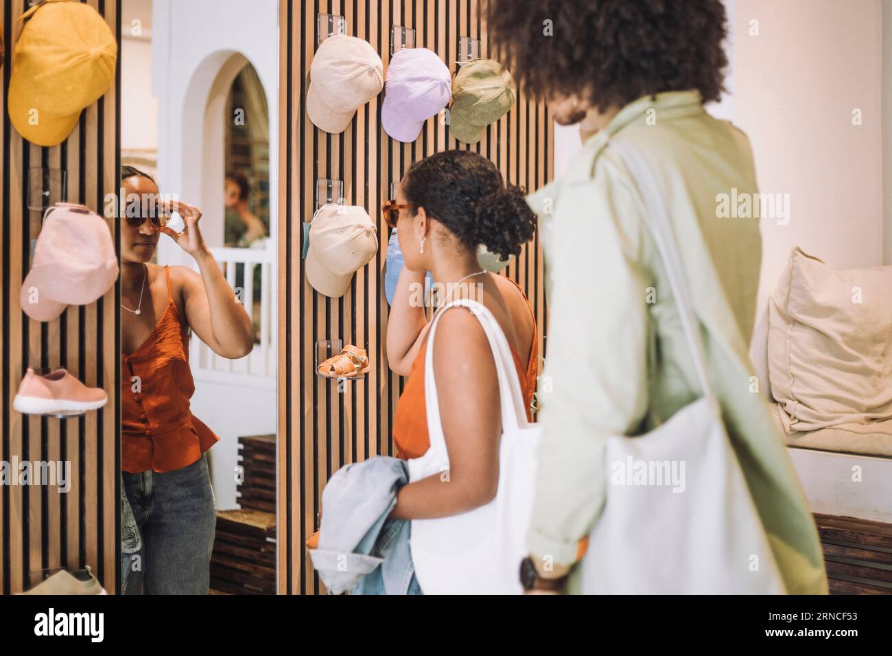 Femme essayant des lunettes de soleil tout en se tenant par l'homme à la boutique de mode Banque D'Images