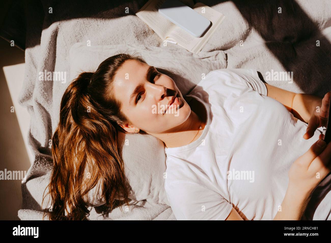 Portrait de la jeune femme souriante posée sur le lit à la maison Banque D'Images