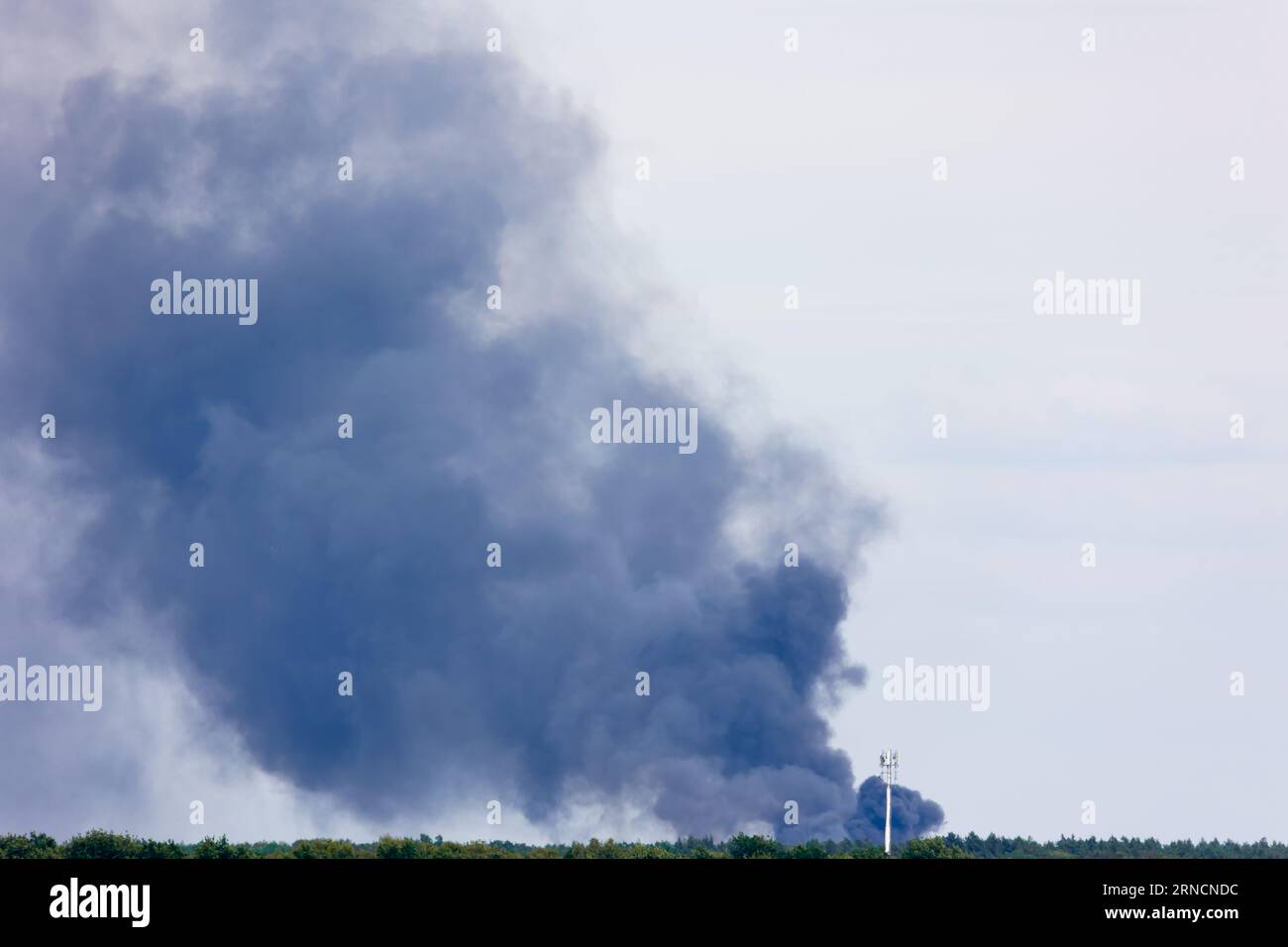 Fumée noire d'un feu s'élevant au-dessus de l'horizon. Pollution de l'air par catastrophe écologique se terminant par un incendie. Photo prise par temps nuageux. Banque D'Images