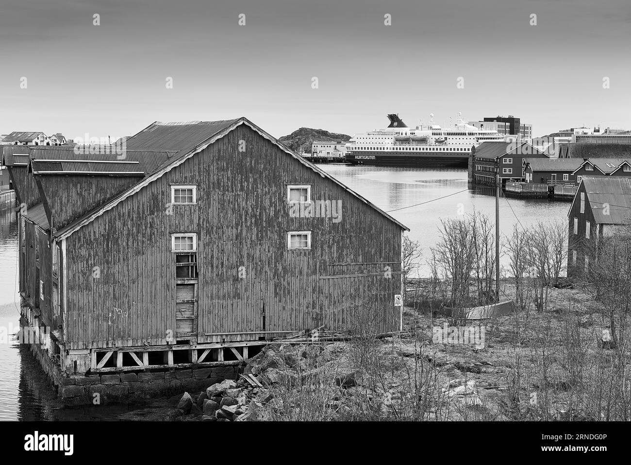 Photo en noir et blanc des entrepôts de poissons norvégiens à l'avant-plan et du ferry Hurtigruten, MS NORDNORGE, amarré à Svolvær, dans les îles Lofoten Banque D'Images Photo en noir et blanc des entrepôts de poissons norvégiens à l'avant-plan et du ferry Hurtigruten, MS NORDNORGE, amarré à Svolvær, dans les îles Lofoten Banque D'Images