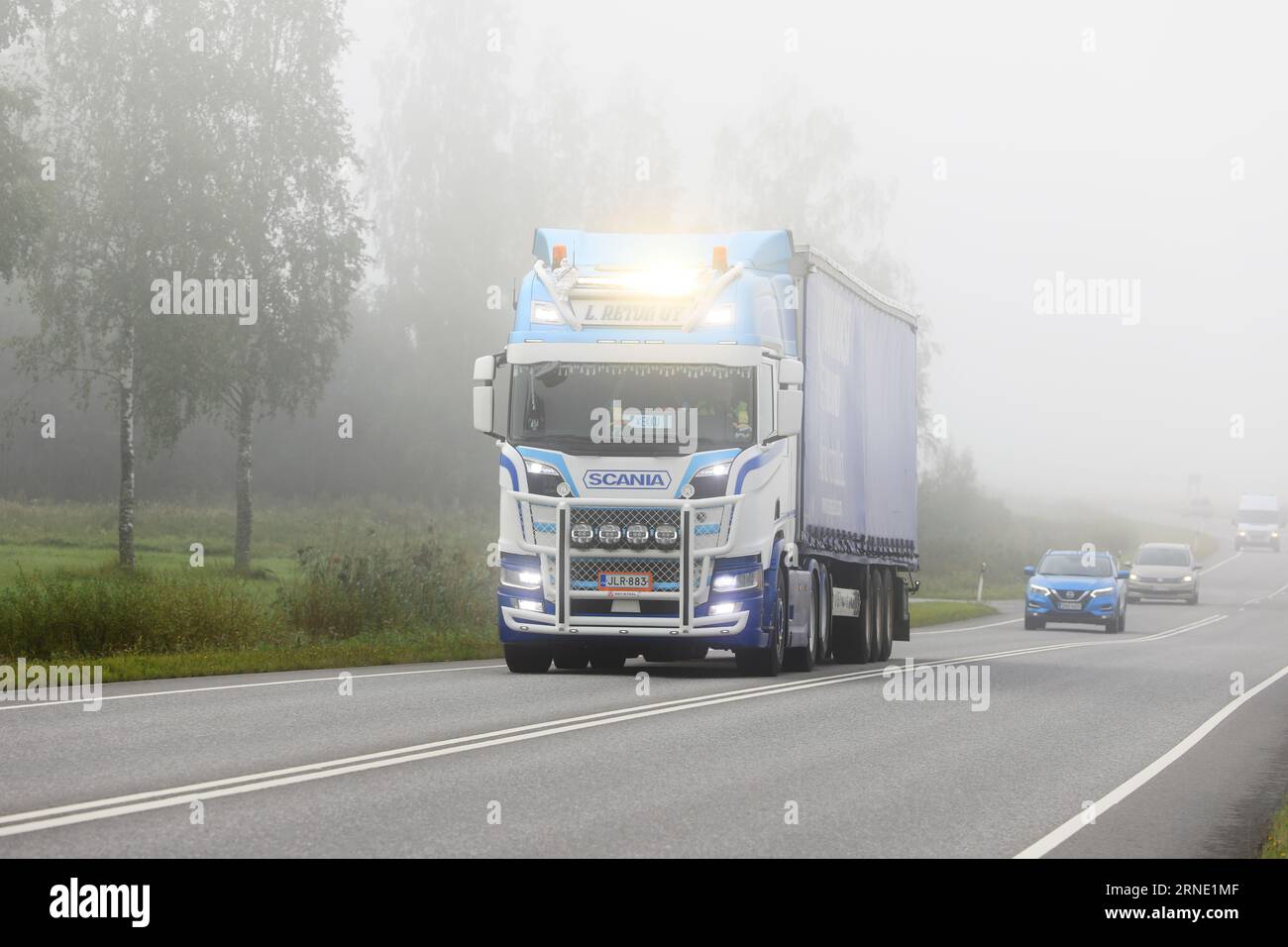 Scania Truck L Retva Oy sur mesure tire une semi-remorque dans la circulation routière par un matin brumeux, feux de route brièvement allumés. Salo, Finlande. 25 août 2023. Banque D'Images