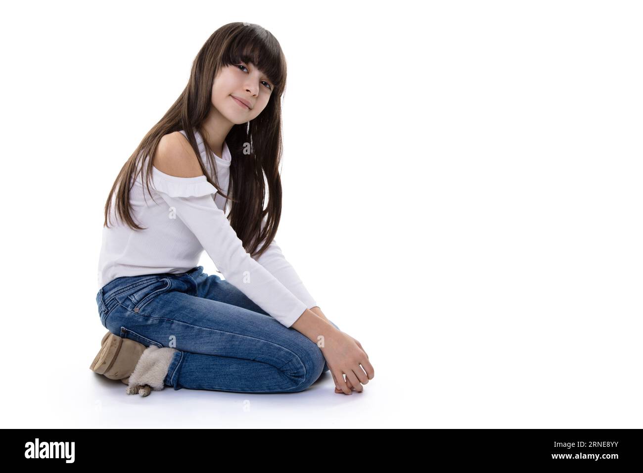 brunette fille s'agenouille sur le sol et sourit dans la caméra avec la tête inclinée légère tout en étant heureuse Banque D'Images