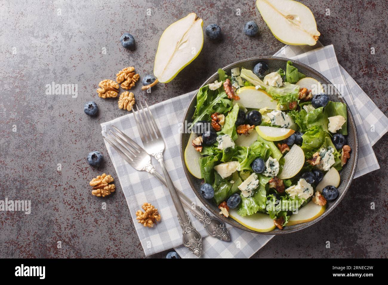 Bleuets, poire, salade de légumes-feuilles avec noix et fromage bleu en gros plan dans une assiette sur la table. vue de dessus horizontale Banque D'Images