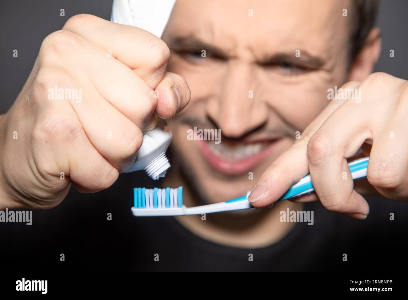 l'homme essaie dur de presser le repos hors du tube vide de dentifrice Banque D'Images