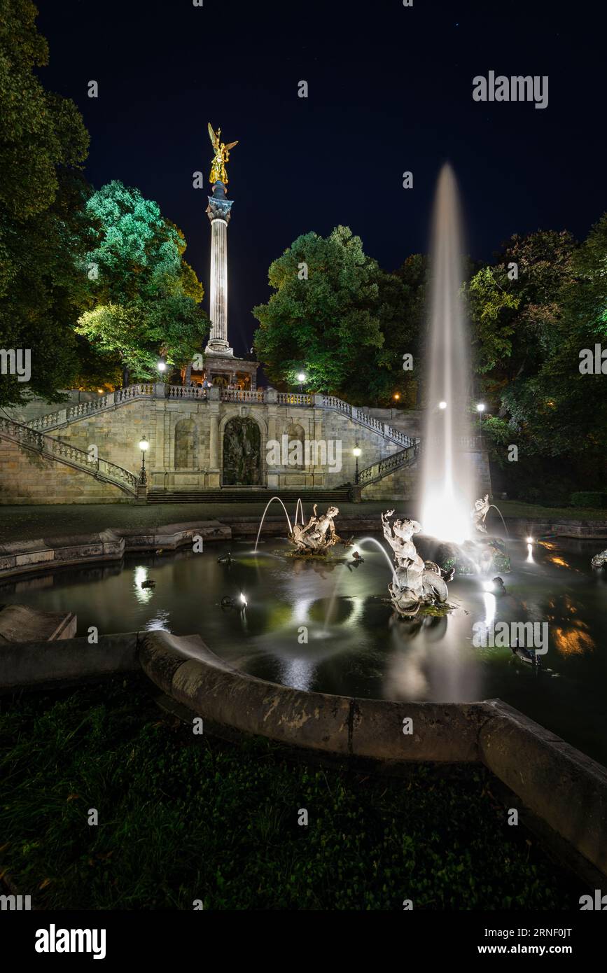 Fontaine avec jets d'eau, sculptures, escaliers et pilier avec l'ange de la paix dans l'illumination nocturne, Bogenhausen, Munich, Allemagne Banque D'Images