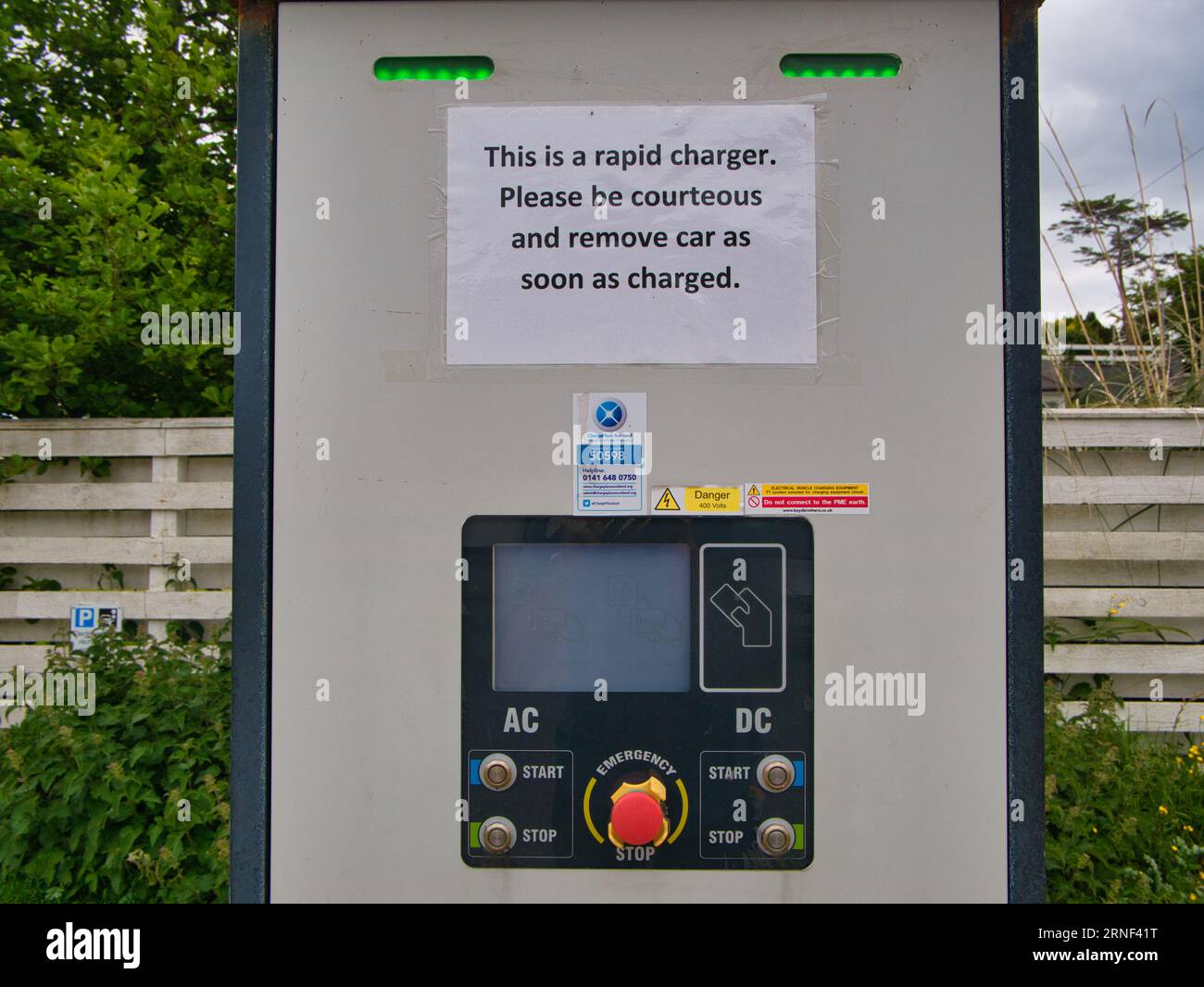 Un chargeur rapide de véhicule électrique avec un panneau demandant aux clients d'être courtois et de déplacer leur voiture lorsqu'elle est chargée. Prise à Tarbert, île de Harr Banque D'Images