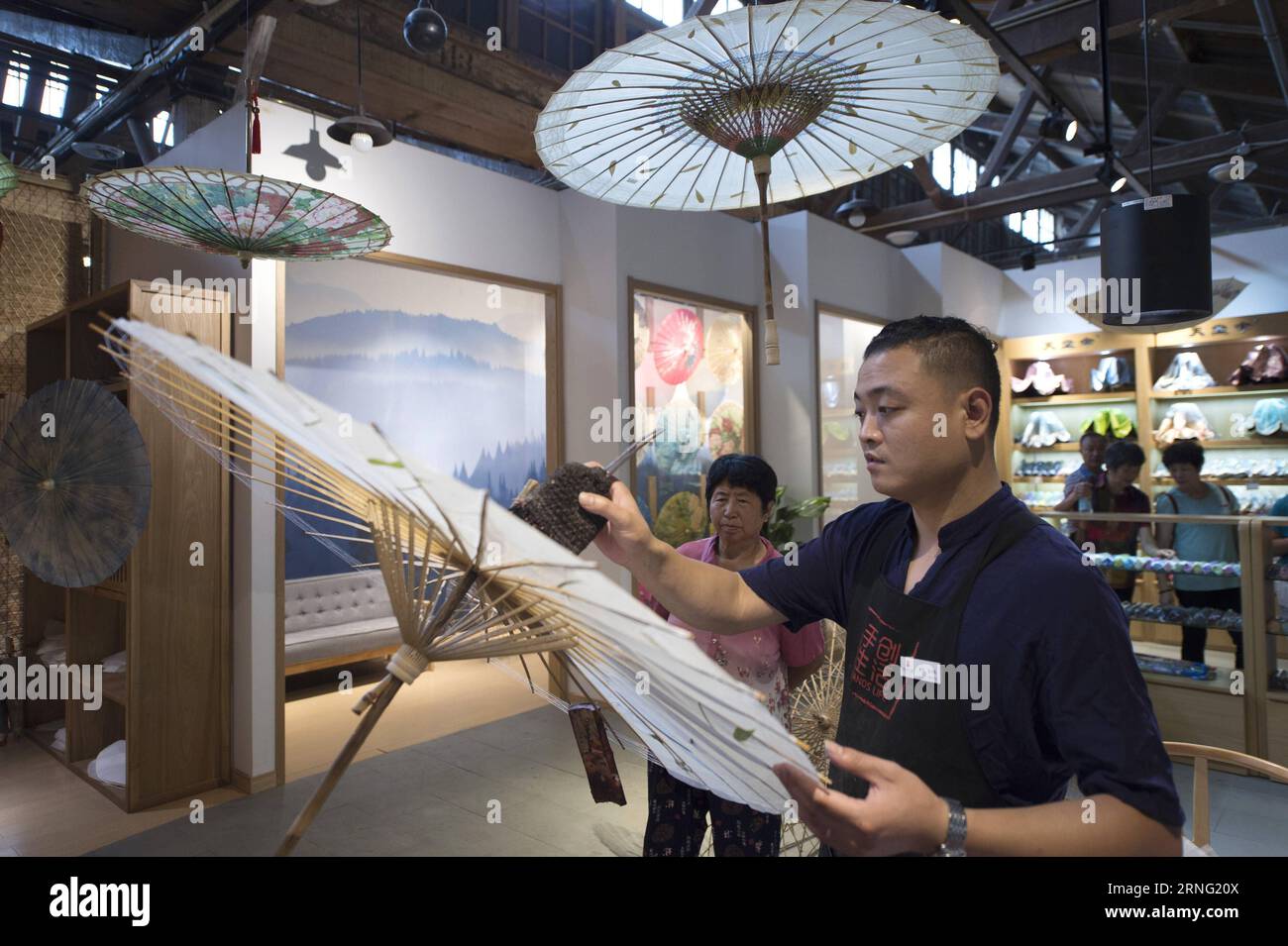 (160902) -- HANGZHOU, 2 septembre 2016 -- Un artiste folklorique démontre la technique de fabrication d'un parapluie en papier huile dans un hall d'exposition d'arts et d'artisanat traditionnels dans le bloc historique Qiaoxi près du pont Gongchen à Hangzhou, capitale de la province du Zhejiang de l'est de la Chine, le 1 septembre 2016. L'artisanat traditionnel et les patrimoines culturels immatériels locaux y ont été exposés. )(mp) (SOMMET G20)CHINA-HANGZHOU-ARTS & CRAFTS-EXPOSITION HALL(CN) JuxHuanzong PUBLICATIONxNOTxINxCHN 160902 Hangzhou sept 2 2016 un artiste folklorique démontre la technique de fabrication de parapluie de papier d'huile À l'exposition Banque D'Images