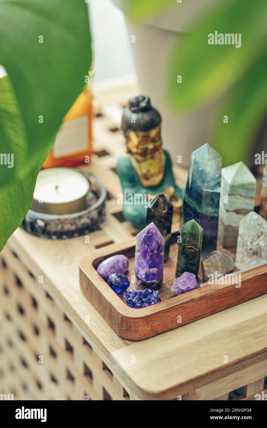 Divers minéraux et cristaux curatifs sur un plateau en bois, statuette de bouddha et bougies en gros plan. Concept de méditation. Banque D'Images