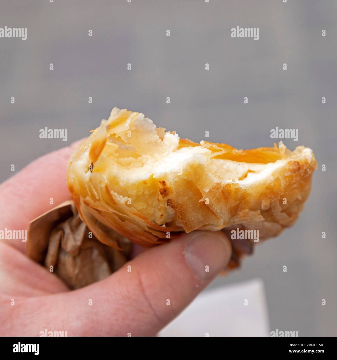 Une personne tient un pastizz rempli de ricotta à la Valette, Malte. Pastizzi sont des pâtisseries salées qui sont une collation maltaise populaire. Banque D'Images