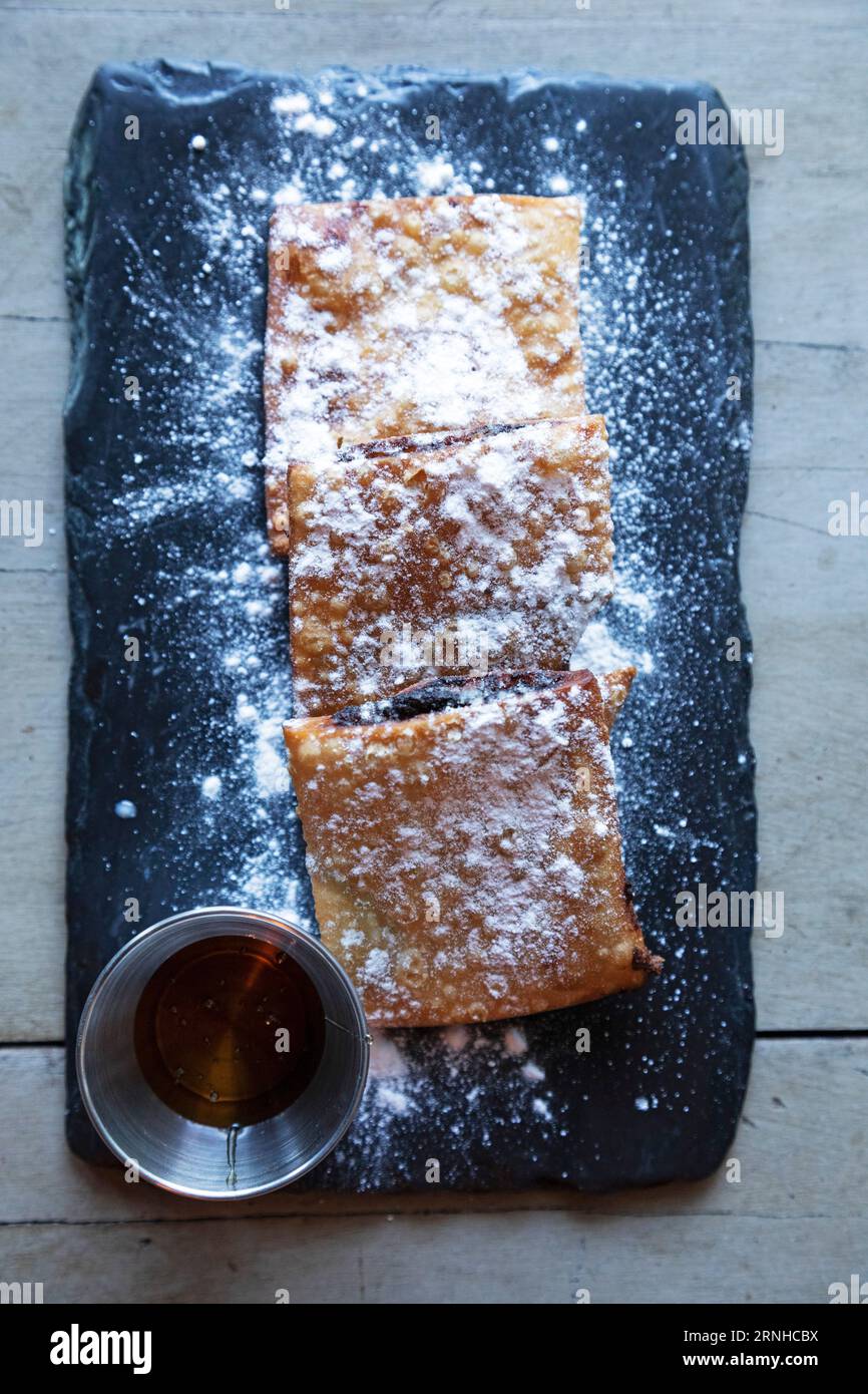 Imqaret, un dessert rempli de dattes au patrimoine arabe, servi à la Valette, Malte. Le plat est servi sur une ardoise avec du sucre en poudre. Banque D'Images