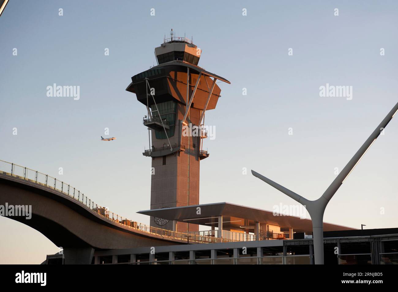 Un avion au départ survole la tour de contrôle de l'aéroport LAX et survole des voies menant à une station pour les passagers du Metro Rail à Los Angeles, CA, États-Unis Banque D'Images