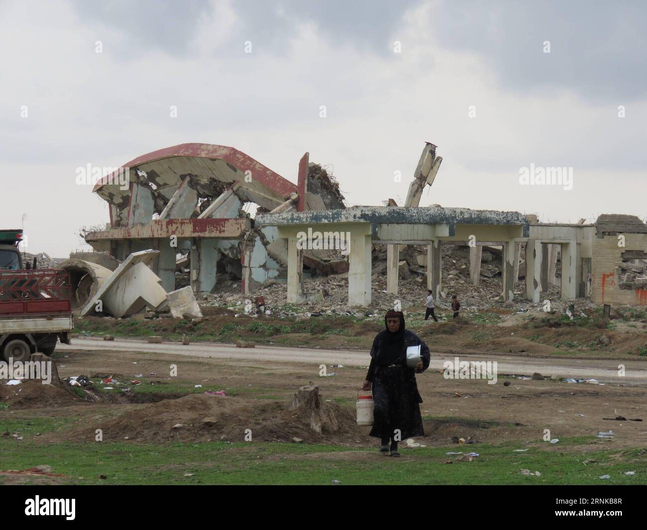 (170320) -- MOSSOUL, le 19 mars 2017 -- Une femme passe devant les ruines d'un bâtiment à l'extérieur du camp de hammam Aleel, en Irak, le 19 mars 2017. À environ 20 km au sud de Mossoul, le camp de hammam Aleel est une plaque tournante importante pour les civils de Mossoul qui doivent être déplacés. Selon un responsable du camp, plus de 35 000 personnes vivaient ici au plus fort, et environ 10 000 personnes sont relocalisées ici à l'heure actuelle.) (dtf) IRAK-MOSSOUL-HAMMAM ALEEL CAMP-RÉFUGIÉS KhalilxDawood PUBLICATIONxNOTxINxCHN Mossoul Mars 19 2017 une femme passe devant les ruines d'un bâtiment à l'extérieur du camp de hammam Irak LE 19 2017 mars À environ 20 km au sud Banque D'Images