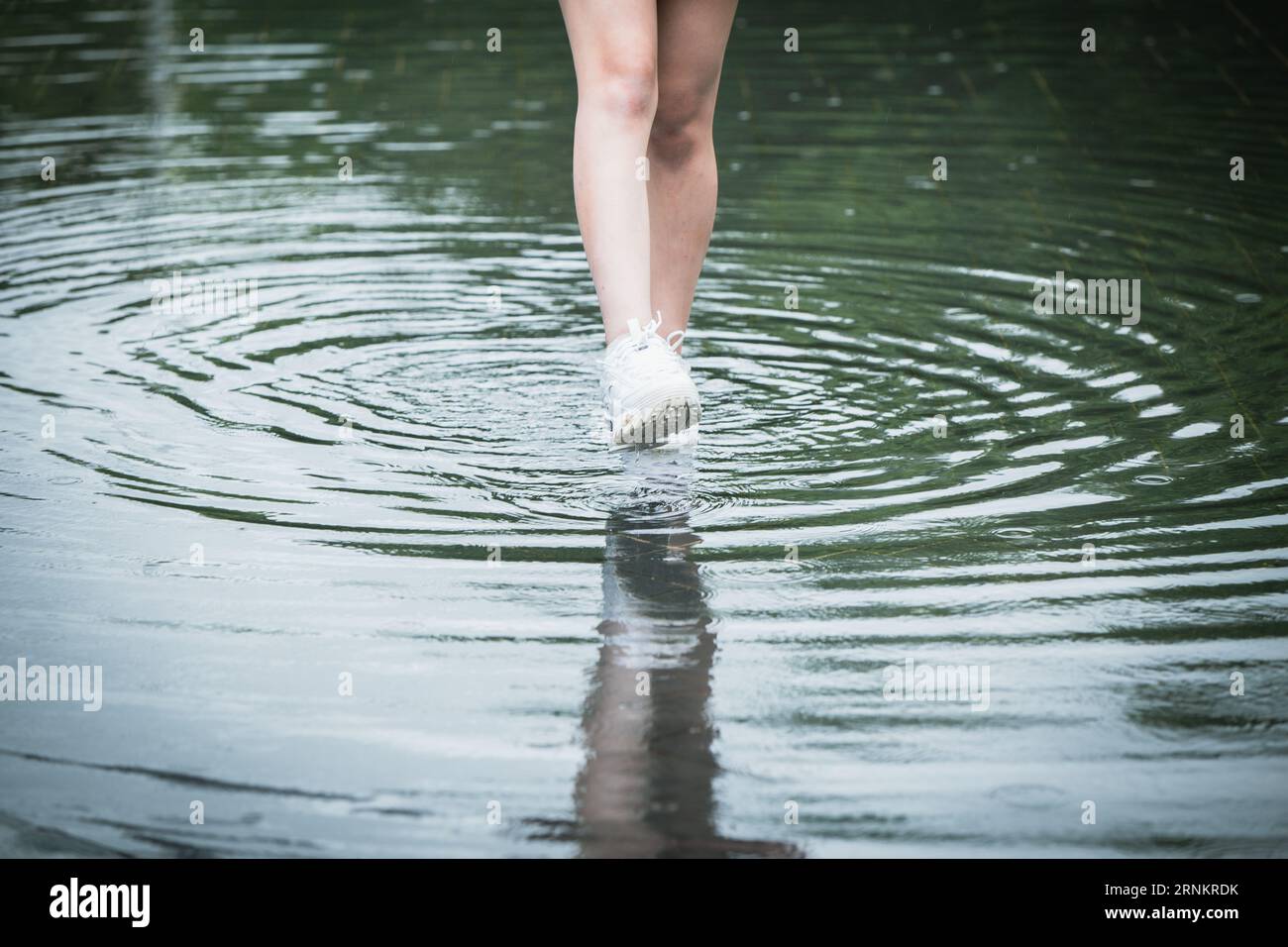 les gens marchent en pataugeant sur la route de rue de la ville d'inondation d'eau après une tempête de pluie forte couse pied mords maladie de peau Banque D'Images