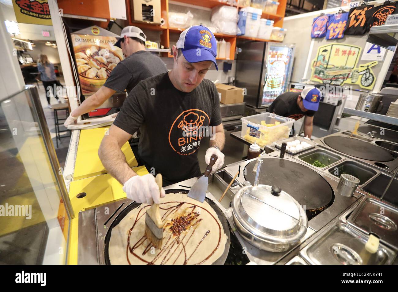 (170425) -- NEW YORK, 25 avril 2017 -- Brian Goldberg fait du jianbing au kiosque de M. Bing dans l'aire de restauration UrbanSpace à New York, aux États-Unis, le 17 avril 2017. UrbanSpace à Midtown New York est un endroit où les cols blancs viennent déjeuner pendant leurs journées de travail. Depuis quelques mois, les clients font toujours la queue devant un kiosque sous une bannière avec des caractères chinois. Ce que ce kiosque vend est une nourriture chinoise très authentique dans le nord de la Chine -- Jianbing, ou la crêpe chinoise. Le kiosque porte la marque MR. Bing et appartient à Brian Goldberg, qui est né et a grandi à New York. Goldberg est très inv Banque D'Images