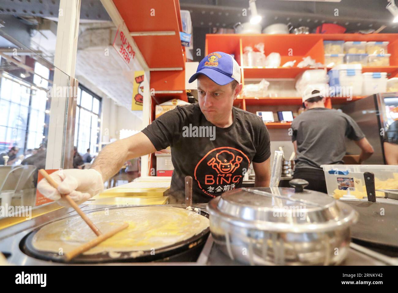 (170425) -- NEW YORK, 25 avril 2017 -- Brian Goldberg fait du jianbing au kiosque de M. Bing dans l'aire de restauration UrbanSpace à New York, aux États-Unis, le 17 avril 2017. UrbanSpace à Midtown New York est un endroit où les cols blancs viennent déjeuner pendant leurs journées de travail. Depuis quelques mois, les clients font toujours la queue devant un kiosque sous une bannière avec des caractères chinois. Ce que ce kiosque vend est une nourriture chinoise très authentique dans le nord de la Chine -- Jianbing, ou la crêpe chinoise. Le kiosque porte la marque MR. Bing et appartient à Brian Goldberg, qui est né et a grandi à New York. Goldberg est très inv Banque D'Images