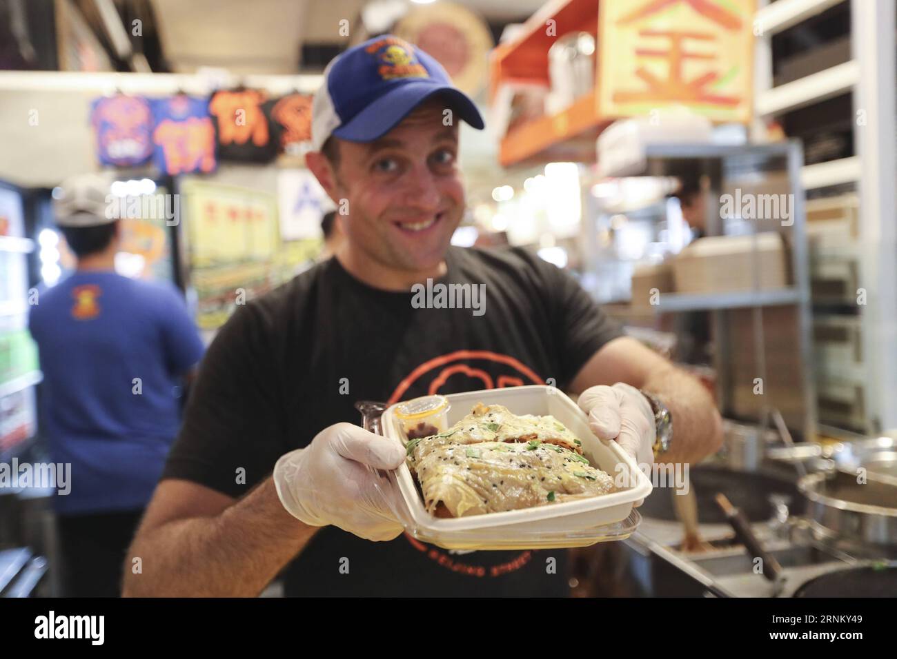 (170425) -- NEW YORK, 25 avril 2017 -- Brian Goldberg montre un Jianbing au kiosque de M. Bing dans l'aire de restauration UrbanSpace à New York, États-Unis, le 17 avril 2017. UrbanSpace à Midtown New York est un endroit où les cols blancs viennent déjeuner pendant leurs journées de travail. Depuis quelques mois, les clients font toujours la queue devant un kiosque sous une bannière avec des caractères chinois. Ce que ce kiosque vend est une nourriture chinoise très authentique dans le nord de la Chine -- Jianbing, ou la crêpe chinoise. Le kiosque porte la marque MR. Bing et appartient à Brian Goldberg, qui est né et a grandi à New York. Goldberg est très moi Banque D'Images