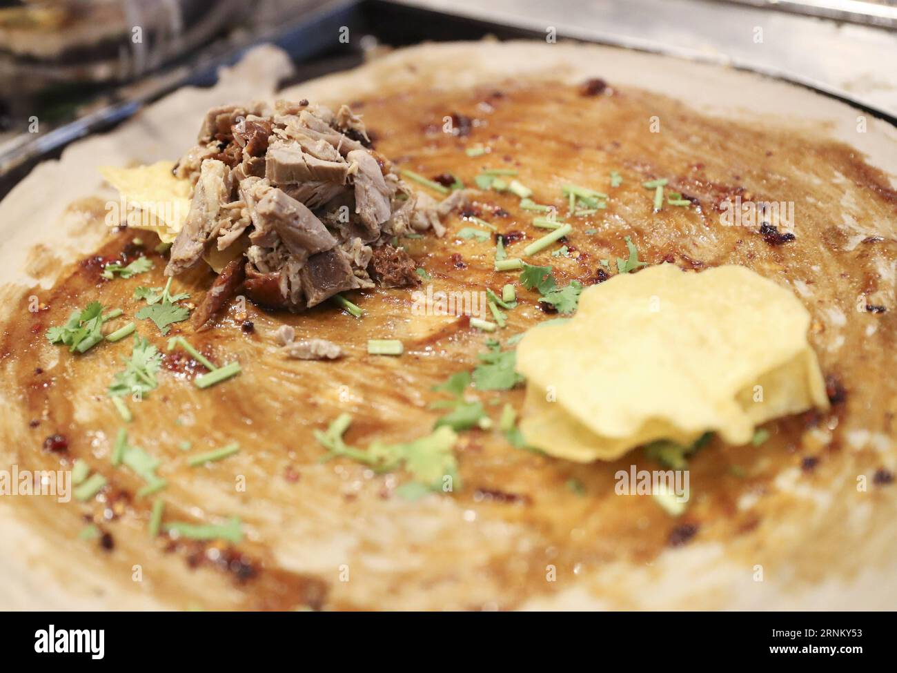 (170425) -- NEW YORK, 25 avril 2017 -- Un Jianbing de la saveur du canard rôti est fait au kiosque de M. Bing dans l'aire de restauration UrbanSpace à New York, aux États-Unis, le 17 avril 2017. UrbanSpace à Midtown New York est un endroit où les cols blancs viennent déjeuner pendant leurs journées de travail. Depuis quelques mois, les clients font toujours la queue devant un kiosque sous une bannière avec des caractères chinois. Ce que ce kiosque vend est une nourriture chinoise très authentique dans le nord de la Chine -- Jianbing, ou la crêpe chinoise. Le kiosque porte la marque MR. Bing et appartient à Brian Goldberg, qui est né et a grandi à New York. G Banque D'Images