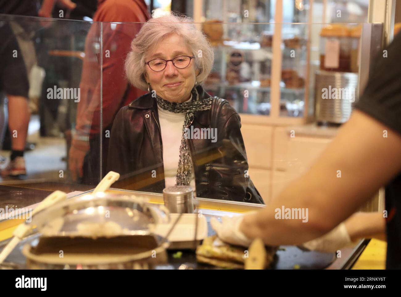 (170425) -- NEW YORK, 25 avril 2017 -- Une cliente attend son Jianbing au kiosque de M. Bing dans l'aire de restauration UrbanSpace à New York, aux États-Unis, le 17 avril 2017. UrbanSpace à Midtown New York est un endroit où les cols blancs viennent déjeuner pendant leurs journées de travail. Depuis quelques mois, les clients font toujours la queue devant un kiosque sous une bannière avec des caractères chinois. Ce que ce kiosque vend est une nourriture chinoise très authentique dans le nord de la Chine -- Jianbing, ou la crêpe chinoise. Le kiosque porte la marque MR. Bing et appartient à Brian Goldberg, qui est né et a grandi à New York. Goldberg est très Banque D'Images