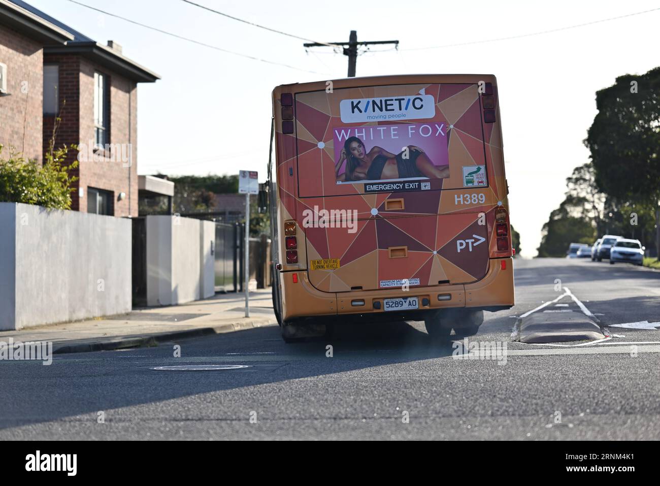 Vue arrière d'un bus Volgren à toit ouvrant PTV, exploité par Kinetic Melbourne, alors qu'il tourne à une intersection tout en émettant des fumées d'échappement Banque D'Images