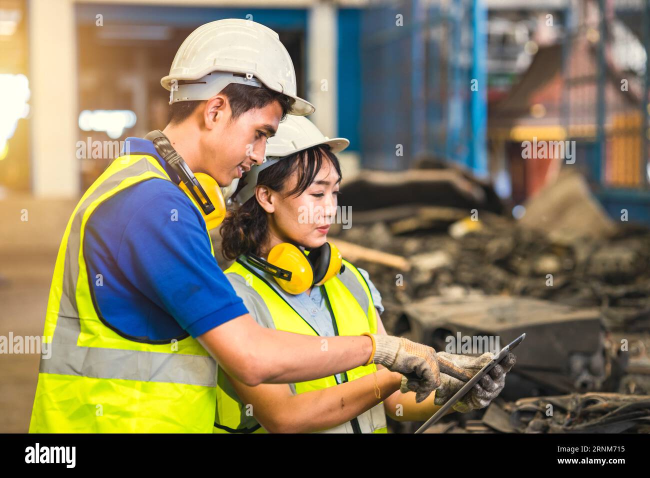 Équipe d'employés d'ingénieur les femmes travaillant avec l'homme travaillent dans le junkyard sale ancien entrepôt de pièces automobiles usagées pour le recyclage ou la réparation Banque D'Images