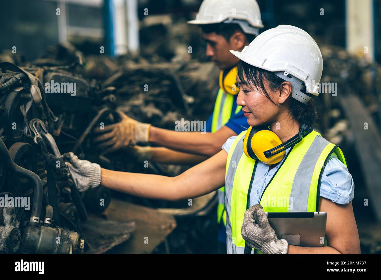 Équipe d'employés d'ingénieur les femmes travaillant avec l'homme travaillent dans le junkyard sale ancien entrepôt de pièces automobiles usagées pour le recyclage ou la réparation Banque D'Images