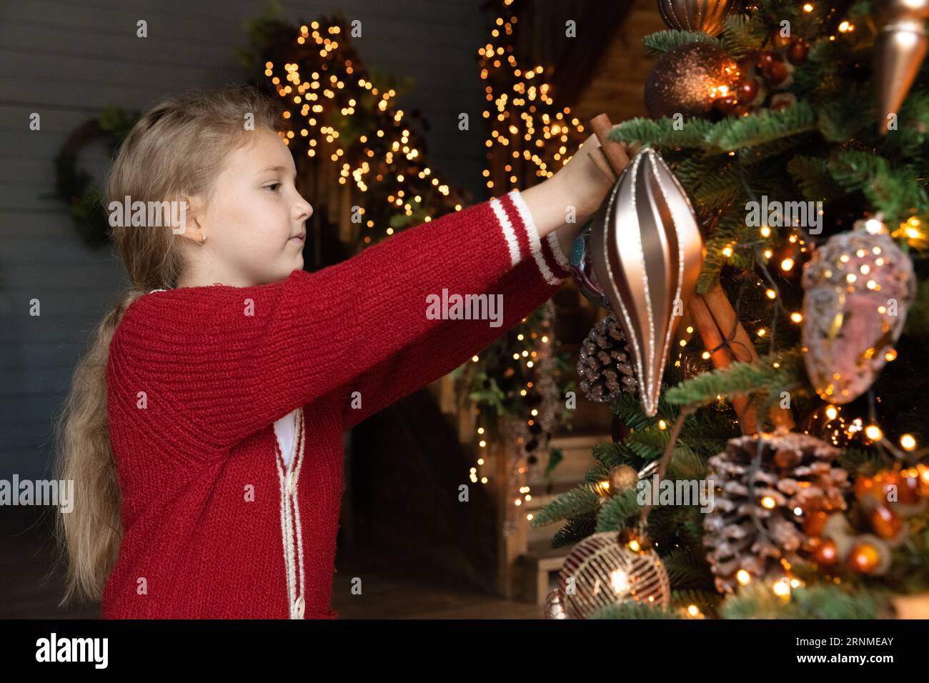 Heureuse adorable petite fille décorant l'arbre de Noël. Banque D'Images