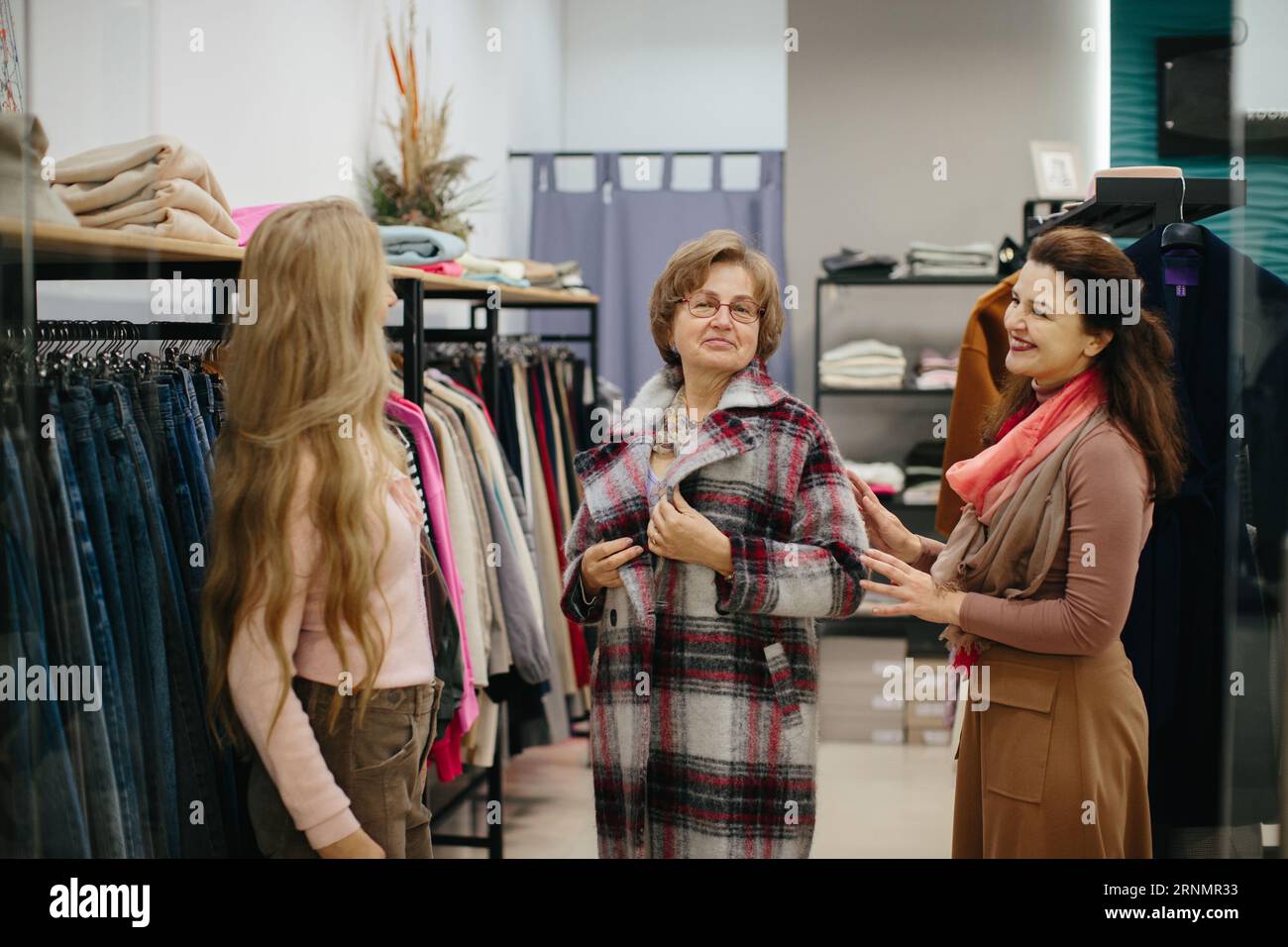 Femme plus âgée essayant des vêtements dans le vestiaire d'un magasin de vêtements Banque D'Images