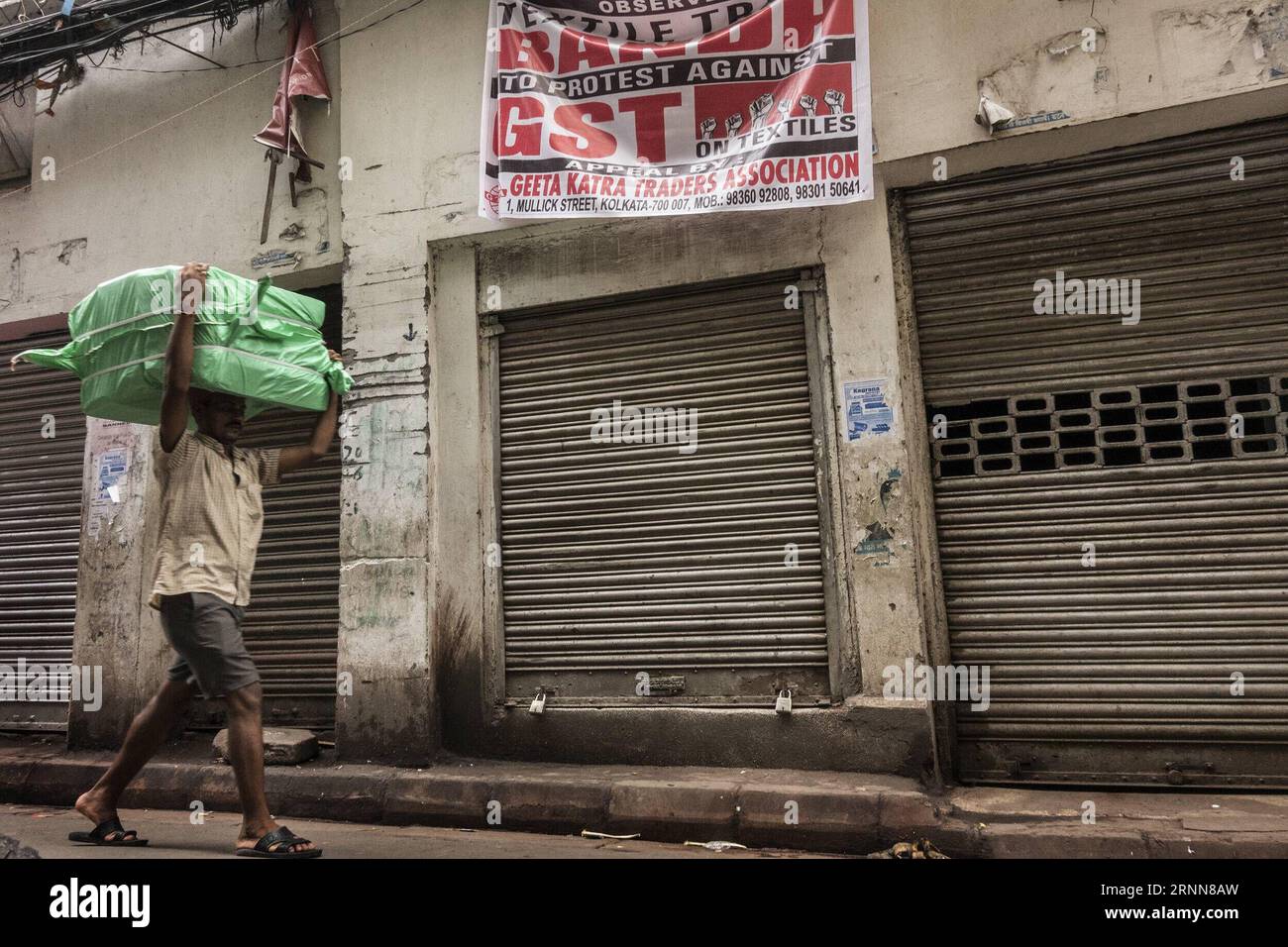 (170630) -- KOLKATA, 30 juin 2017 -- un ouvrier indien passe devant des magasins fermés pendant la grève contre la mise en œuvre de la taxe nationale sur les biens et services (GST) à Kolkata, capitale de l'État indien oriental du Bengale occidental, le 30 juin 2017. La taxe sur les produits et services (GST) est une taxe indirecte dans toute l'Inde pour remplacer les taxes prélevées par le gouvernement central et les gouvernements des États. (Xinhua photo/) (lrz) INDIA-KOLKATA-STRIKE-GOODS AND SERVICES TAX TumpaxMondal PUBLICATIONxNOTxINxCHN Kolkata juin 30 2017 à Indian Laboratory marche devant les magasins fermés pendant la grève contre la mise en œuvre de la nation Banque D'Images