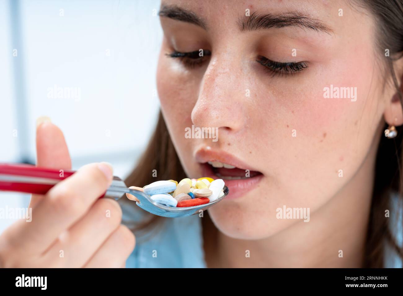 une fille apporte une cuillère remplie de pilules à sa bouche. la notion de médication incontrôlée et de toxicomanie Banque D'Images
