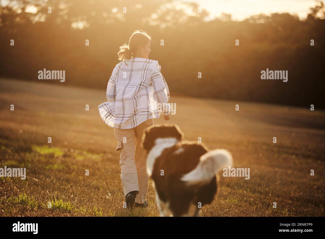 Vue arrière de l'adolescente heureuse tout en courant avec son chien sur le terrain dans le paysage d'automne. Joyeux propriétaire d'animal de compagnie avec chien de montagne tchèque. Banque D'Images