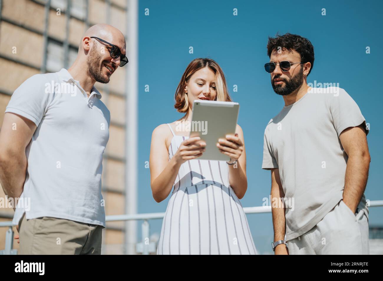 Jeunes architectes et hommes d'affaires collaborant à l'extérieur, discutant de la conception architecturale avec plan sur la table, créant un plan de construction moderne. Banque D'Images