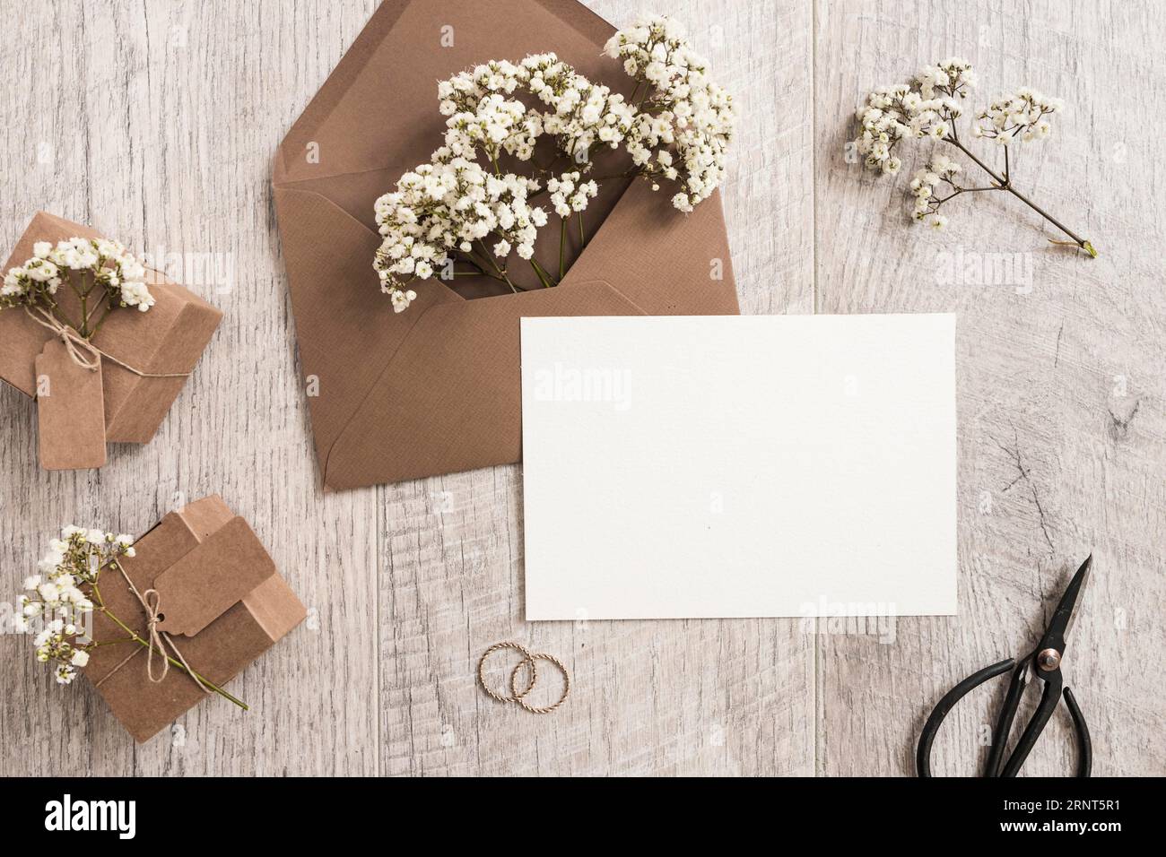 Enveloppe marron avec bébé s souffle fleurs boîtes cadeaux anneaux mariage  ciseaux fond en bois carte blanche Photo Stock - Alamy