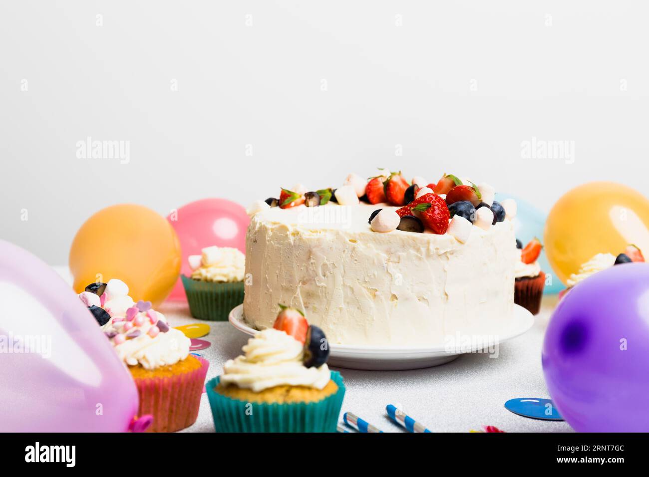 Gros gâteau avec différentes baies près des ballons d'air Banque D'Images