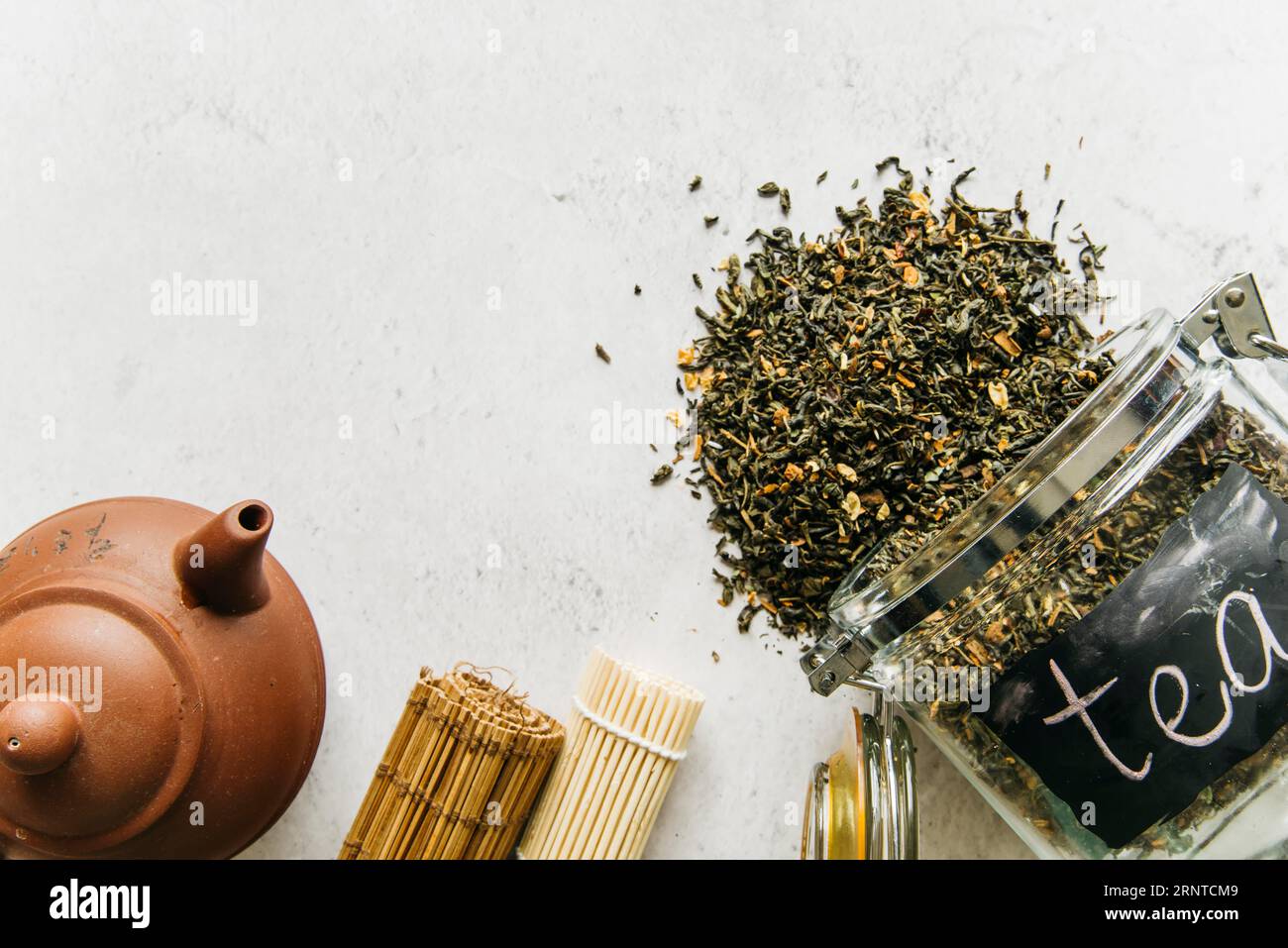 Théière en argile enroulée avec thé aux herbes séché renversé du pot en verre Banque D'Images Théière en argile enroulée avec thé aux herbes séché renversé du pot en verre Banque D'Images