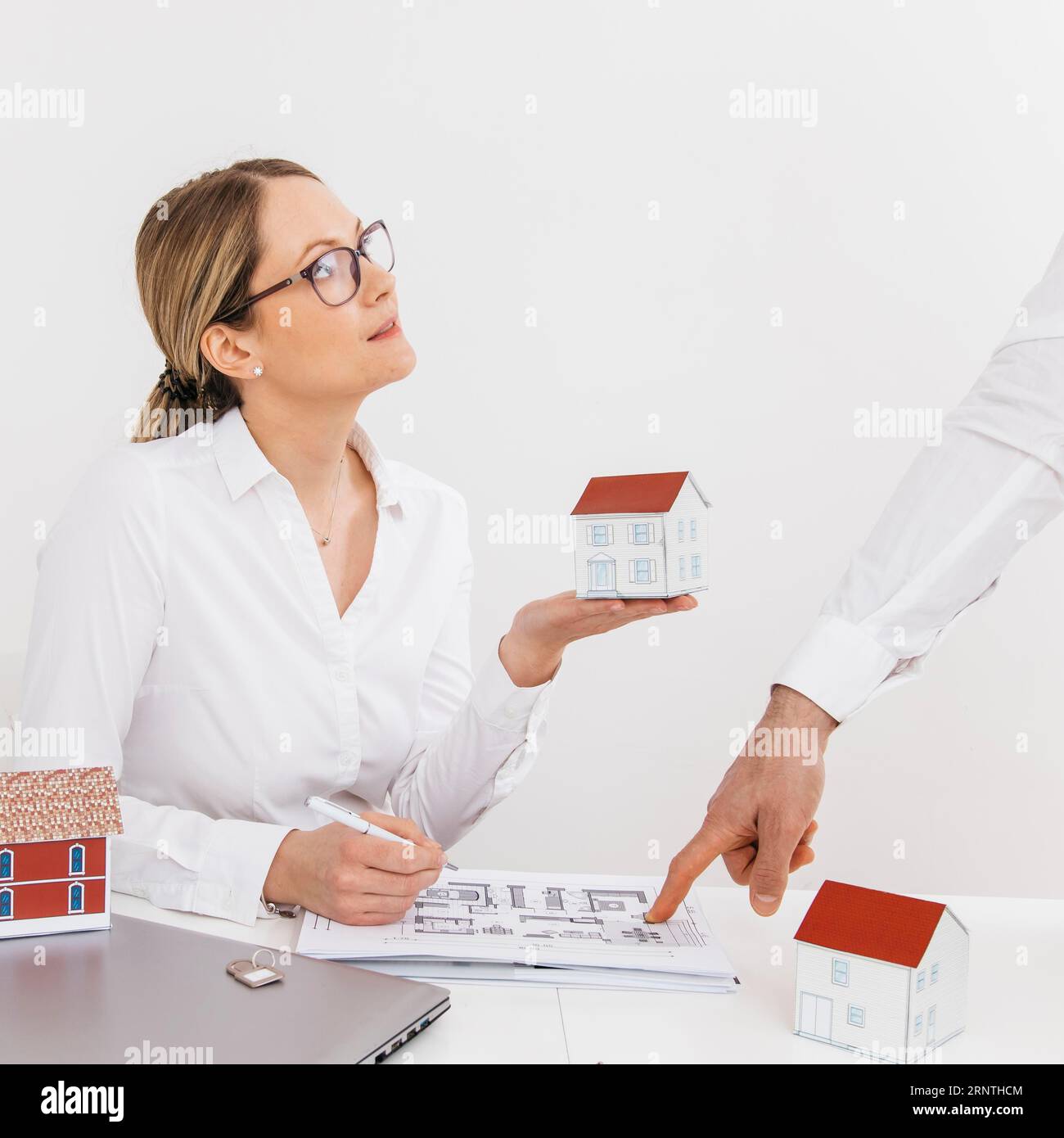 Femme tenant le modèle de maison regardant son collègue pointant le bureau d'impression bleu Banque D'Images
