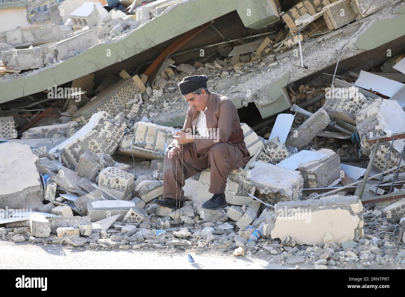 (171114) -- SULAIMANIYAH (IRAK), 14 novembre 2017 -- un homme est assis dans les ruines d'un bâtiment effondré dans la ville de Darbandikhan, province de Sulaimaniyah, Nord de l'Irak, le 14 novembre 2017. Dimanche, un énorme tremblement de terre a frappé la région le long de la frontière nord entre l'Iran et l'Irak, faisant au moins 454 morts et plus de 7 800 blessés. IRAK-SULAIMANIYAH-TREMBLEMENT DE TERRE KhalilxDawood PUBLICATIONxNOTxINxCHN Banque D'Images