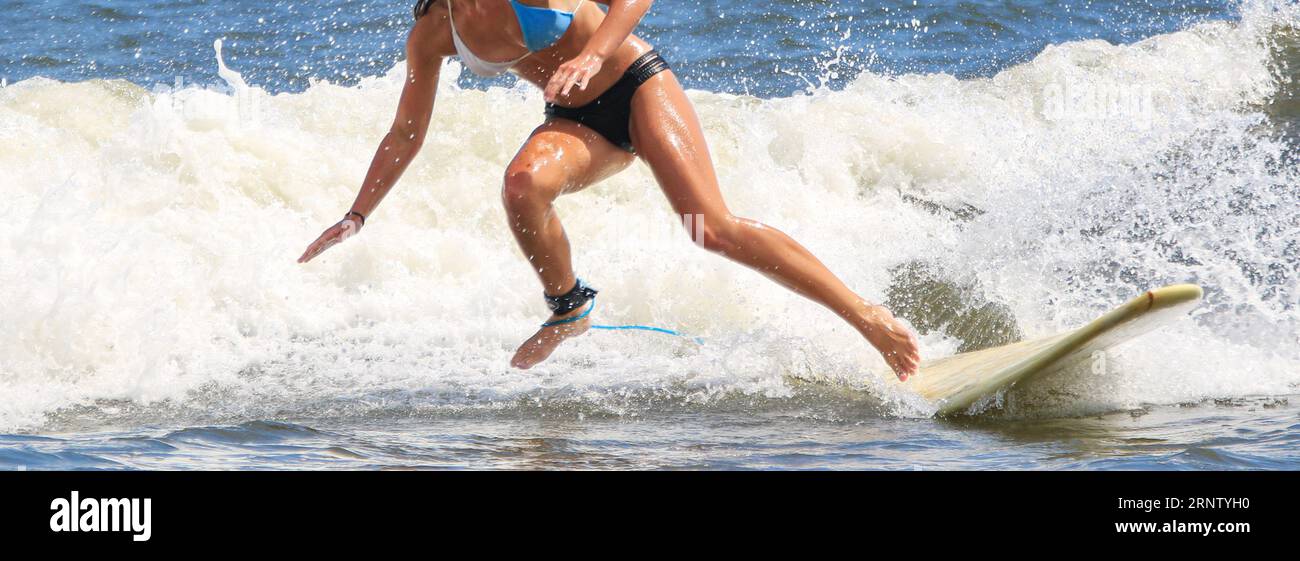 Vue de face d'une adolescente portant un bikini tombant de son surf dans l'eau alors qu'elle surfait à Gilgo Beach sur long Island New York. Banque D'Images