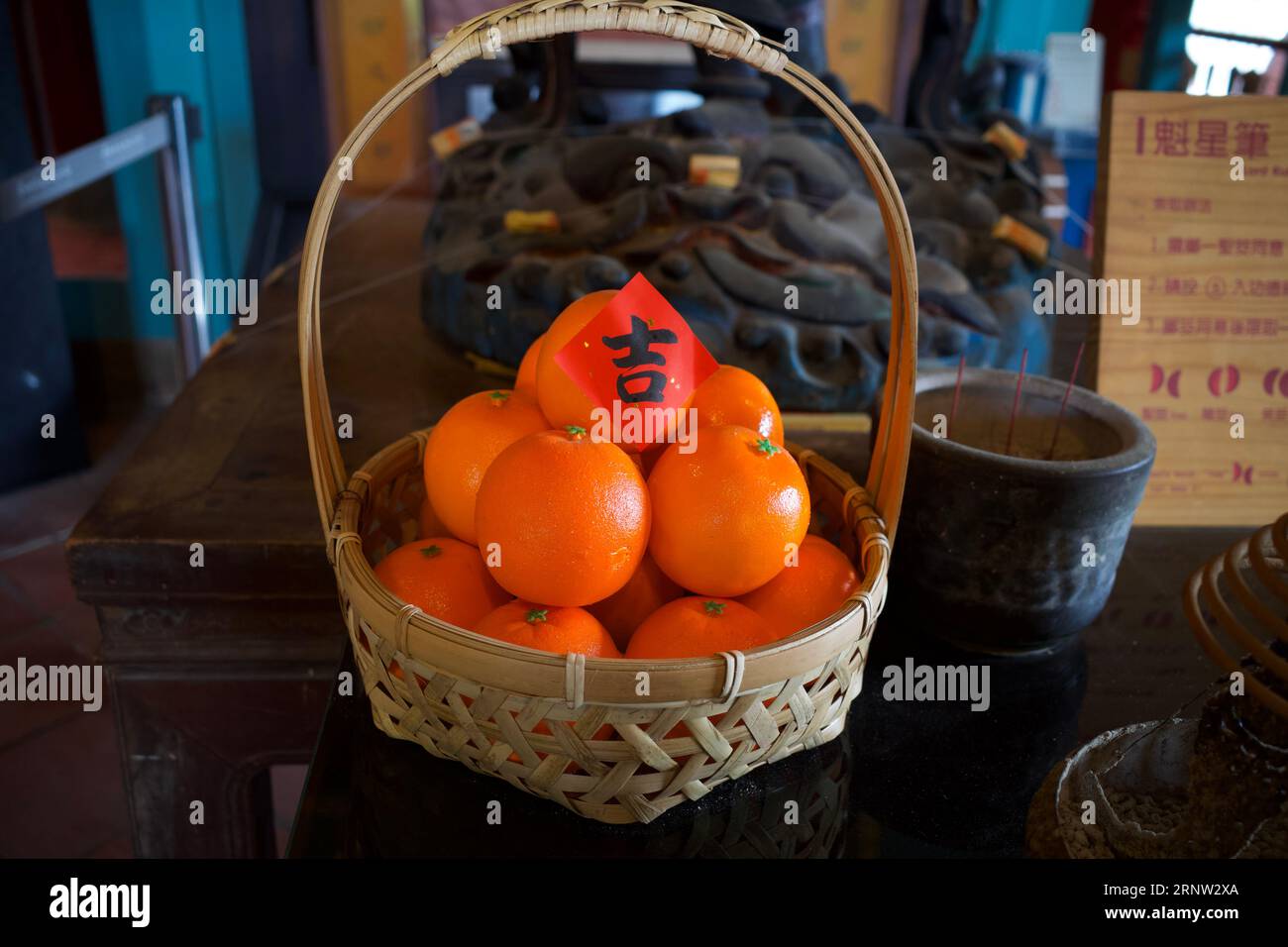 Un panier de mandarines a été placé sur une table d'un sanctuaire. Le papier rouge sur le dessus est un caractère chinois qui signifie auspicieux. Banque D'Images