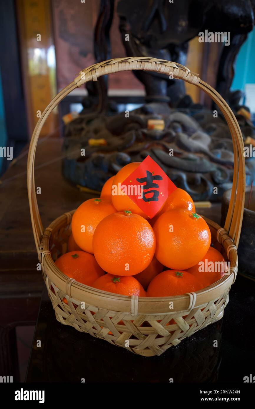 Un panier de mandarines a été placé sur une table d'un sanctuaire. Le papier rouge sur le dessus est un caractère chinois qui signifie auspicieux. Banque D'Images